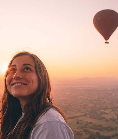 image of the a girl looking upwards with a hot air balloon in the background.